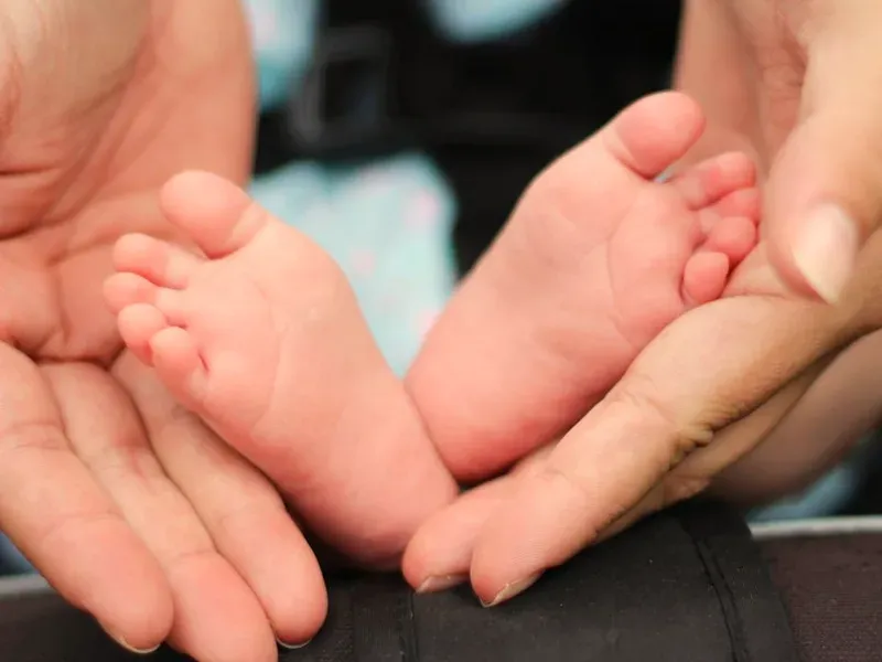 Pieds d'un nourrisson reposant dans les mains de ses parents